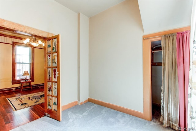 interior space with vaulted ceiling, an inviting chandelier, and hardwood / wood-style floors