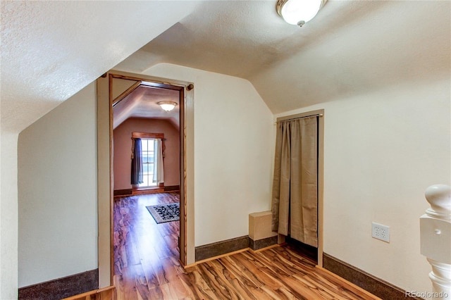 bonus room featuring a textured ceiling, vaulted ceiling, and wood-type flooring