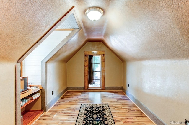 bonus room featuring a textured ceiling, light hardwood / wood-style flooring, and lofted ceiling