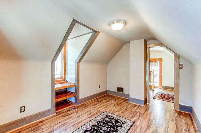 bonus room with vaulted ceiling and light hardwood / wood-style flooring