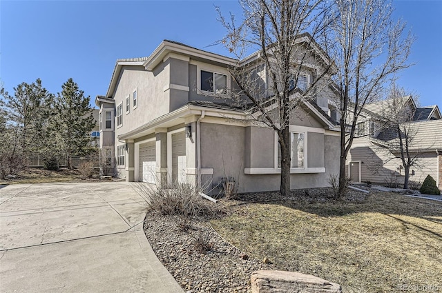 view of side of home featuring a garage, driveway, and stucco siding