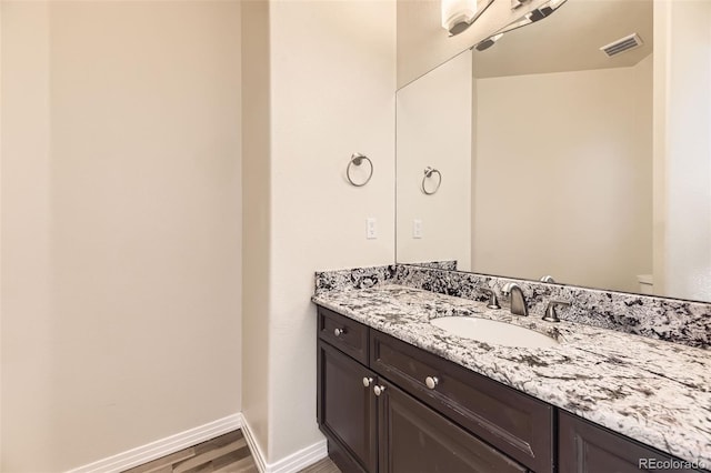 bathroom featuring visible vents, vanity, baseboards, and wood finished floors