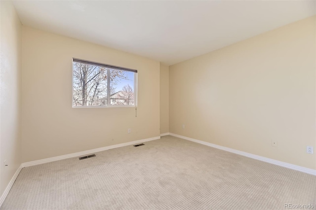 empty room with baseboards, visible vents, and light colored carpet