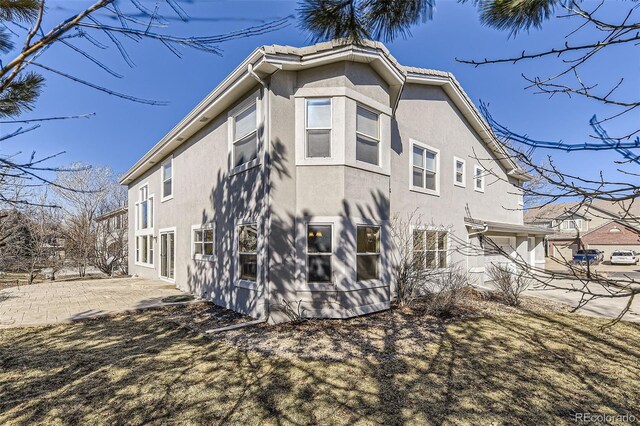 rear view of house with a patio area and stucco siding