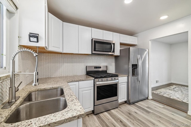 kitchen with sink, light stone counters, tasteful backsplash, appliances with stainless steel finishes, and white cabinets