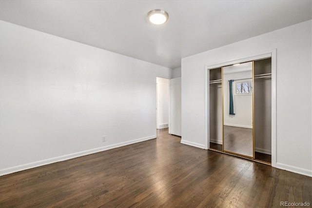 unfurnished bedroom featuring a closet, baseboards, and dark wood-type flooring