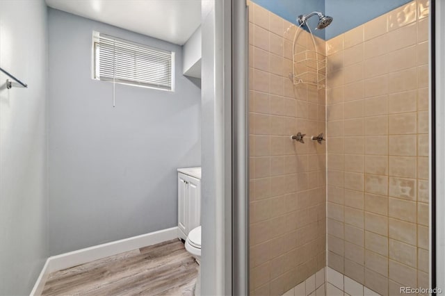 bathroom with a stall shower, wood finished floors, toilet, and baseboards