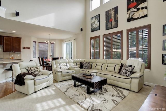 living room with a high ceiling, a notable chandelier, light carpet, and plenty of natural light