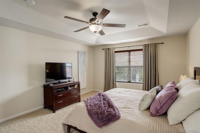 carpeted bedroom with ceiling fan and a tray ceiling