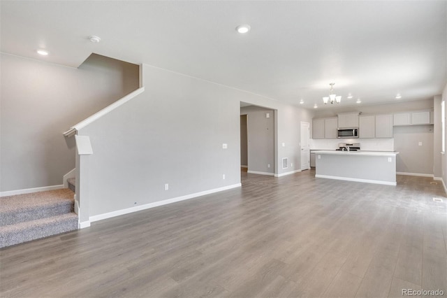 unfurnished living room with a notable chandelier and light wood-type flooring