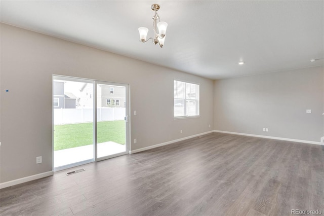 spare room featuring hardwood / wood-style floors and a notable chandelier