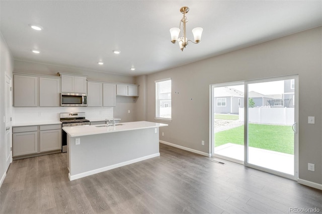 kitchen featuring appliances with stainless steel finishes, an inviting chandelier, light hardwood / wood-style flooring, and pendant lighting