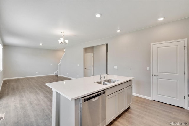 kitchen featuring a kitchen island with sink, sink, stainless steel dishwasher, and light wood-type flooring