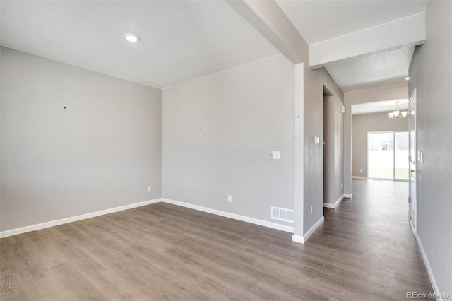 empty room featuring hardwood / wood-style floors and an inviting chandelier