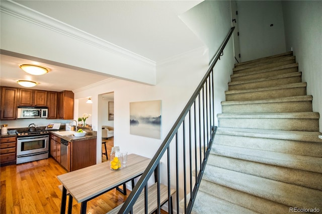 stairway featuring hardwood / wood-style flooring, crown molding, and sink