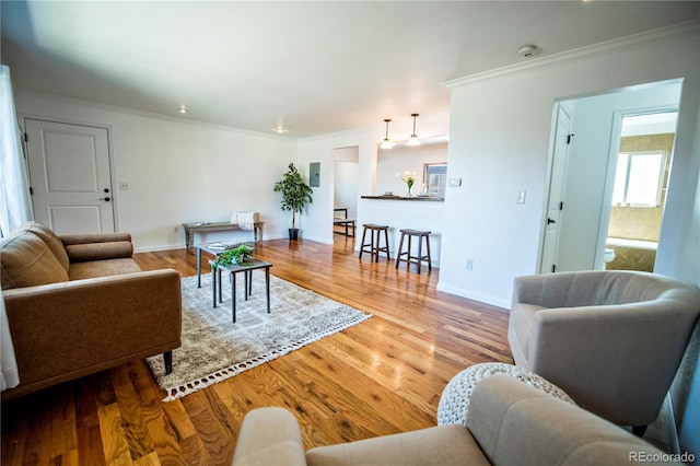 living room with ornamental molding, baseboards, and wood finished floors