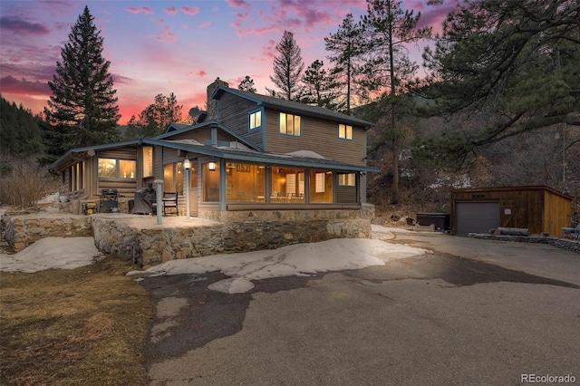 view of front facade with an outbuilding, stone siding, and aphalt driveway