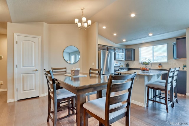 12718 Windingwalk Dr, Peyton, CO 80831 - dining area with light wood-type flooring, a chandelier, lofted ceiling, baseboards, and recessed lighting