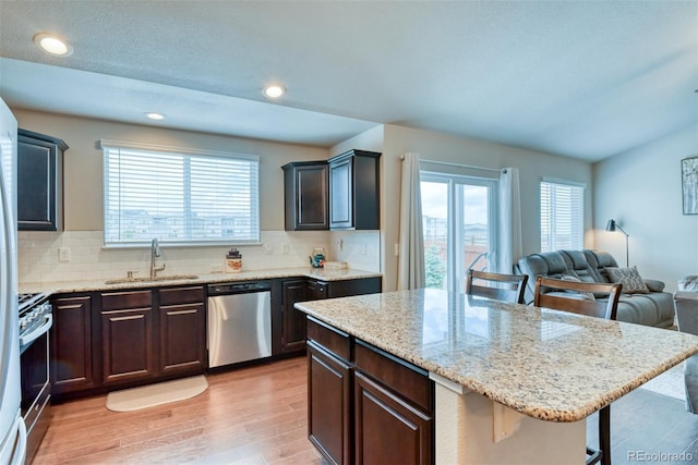 12718 Windingwalk Dr, Peyton, CO 80831 - kitchen with appliances with stainless steel finishes, a sink, a kitchen breakfast bar, light wood-type flooring, and tasteful backsplash