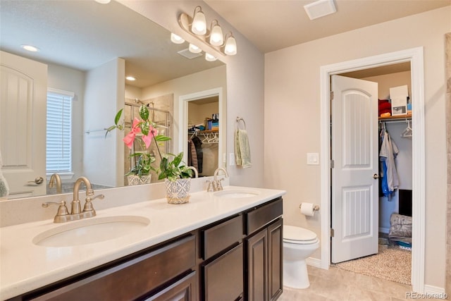 12718 Windingwalk Dr, Peyton, CO 80831 - full bath with double vanity, toilet, a spacious closet, a shower, and tile patterned flooring
