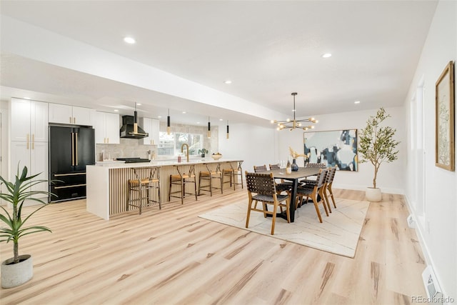 dining room with a notable chandelier, light hardwood / wood-style floors, and sink