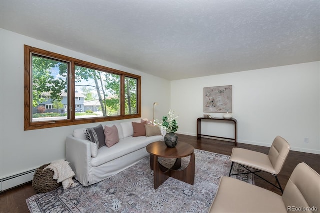 living room featuring a healthy amount of sunlight, a baseboard heating unit, wood-type flooring, and a textured ceiling