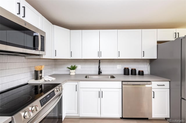 kitchen with white cabinets, sink, appliances with stainless steel finishes, and backsplash