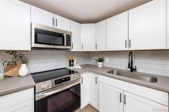 kitchen with backsplash, sink, stainless steel appliances, and white cabinets