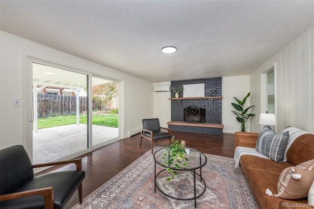 living room with a fireplace, brick wall, hardwood / wood-style flooring, an AC wall unit, and a textured ceiling