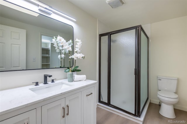 bathroom with hardwood / wood-style floors, vanity, toilet, and a shower with shower door