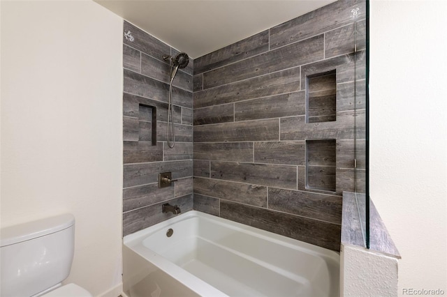 bathroom featuring toilet and tiled shower / bath