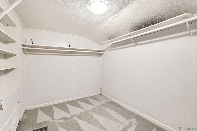 walk in closet featuring light carpet and vaulted ceiling