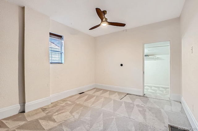 empty room featuring a ceiling fan, visible vents, light carpet, and baseboards