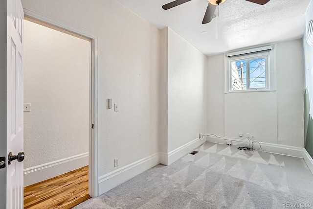 clothes washing area with a textured ceiling, ceiling fan, light carpet, and baseboards