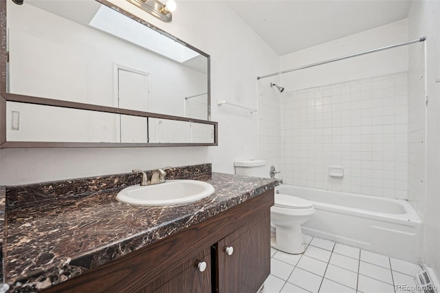 full bathroom with toilet, tiled shower / bath, a skylight, vanity, and tile patterned flooring