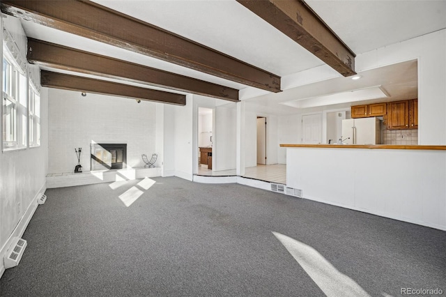 unfurnished living room featuring beam ceiling, light colored carpet, and a fireplace