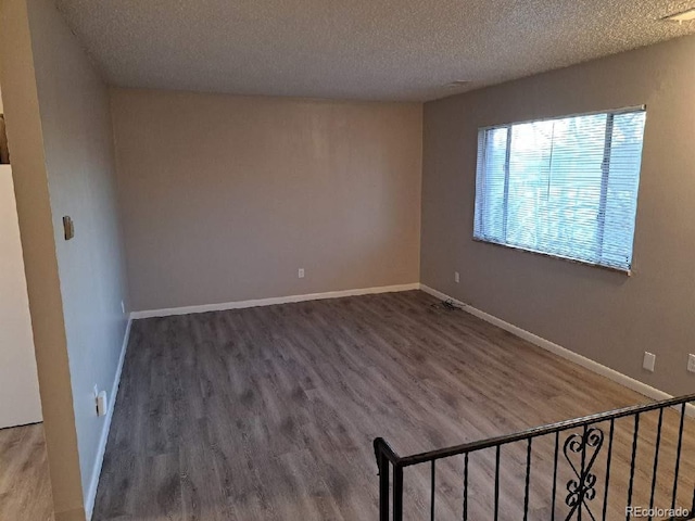 spare room featuring wood-type flooring and a textured ceiling