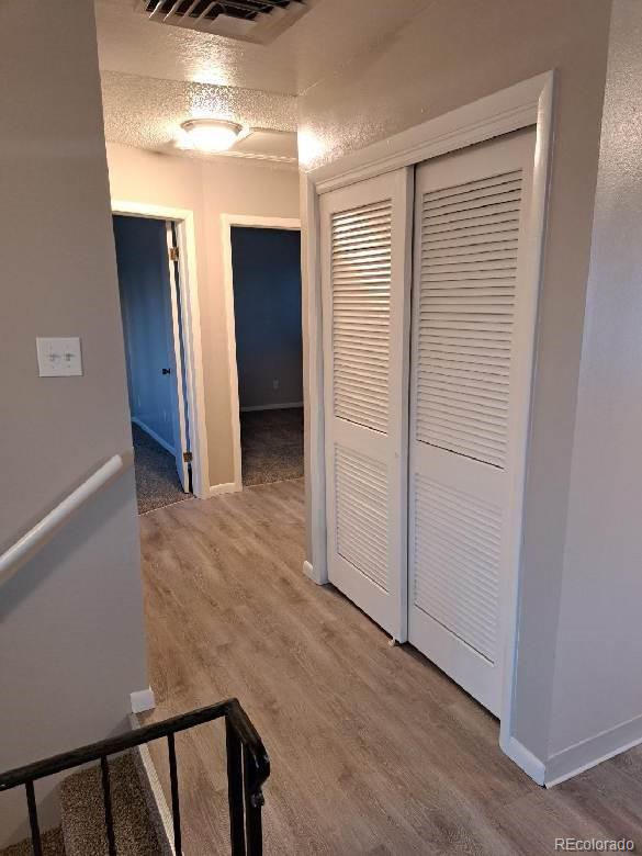 hall featuring wood-type flooring and a textured ceiling