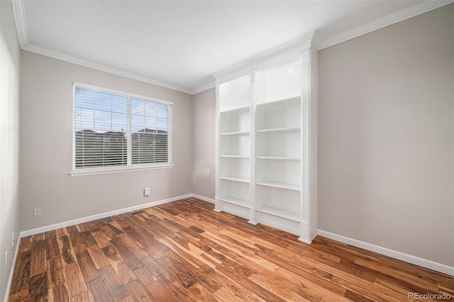 empty room with crown molding, baseboards, and wood finished floors