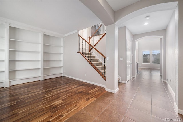 entryway with stairs, arched walkways, baseboards, and wood finished floors