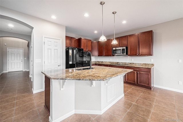 kitchen featuring arched walkways, light stone countertops, a sink, black appliances, and recessed lighting