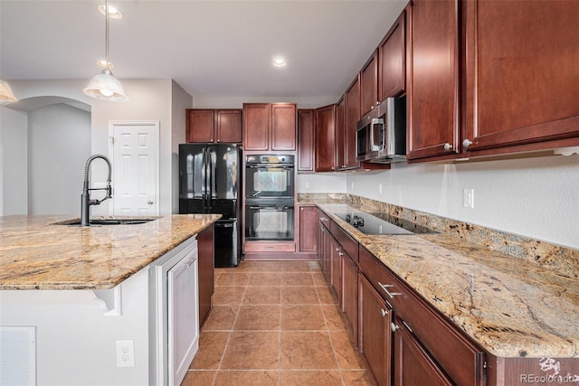 kitchen featuring decorative light fixtures, light stone countertops, a sink, and black appliances
