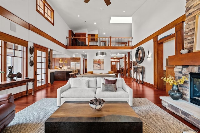 living room featuring dark hardwood / wood-style flooring, a fireplace, high vaulted ceiling, and ceiling fan