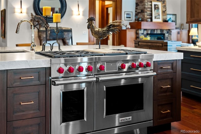 kitchen featuring dark brown cabinetry, dark hardwood / wood-style floors, sink, and range with two ovens