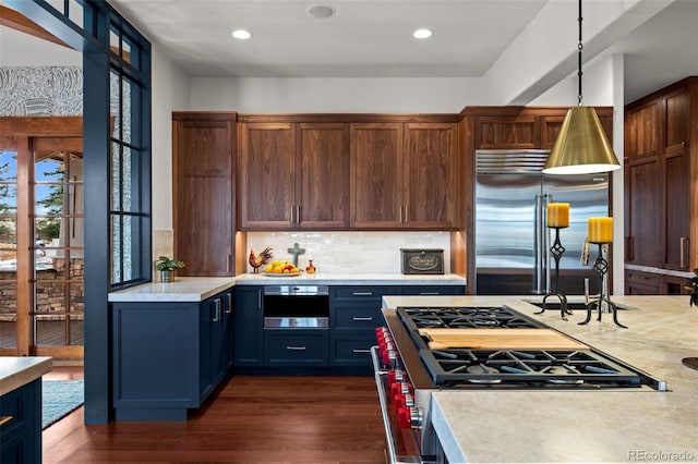 kitchen with sink, dark hardwood / wood-style flooring, pendant lighting, stainless steel appliances, and backsplash