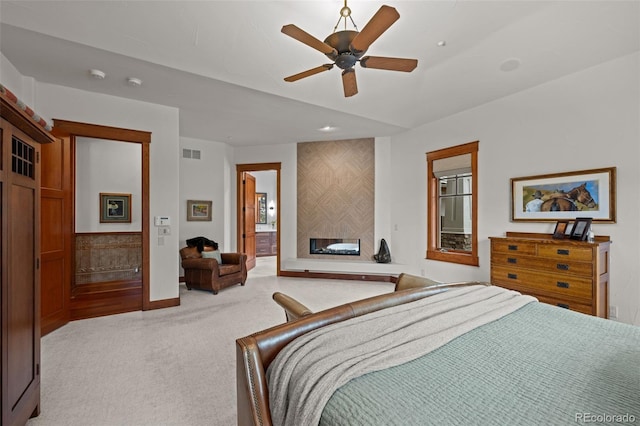 bedroom with ceiling fan, ensuite bathroom, a fireplace, and light carpet