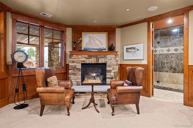 living area with ornamental molding, a fireplace, light carpet, and wood walls