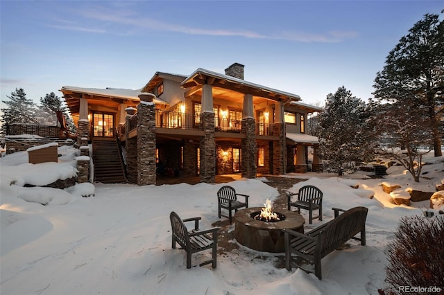 snow covered rear of property featuring a fire pit and a balcony