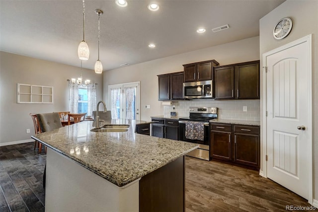 kitchen featuring pendant lighting, sink, dark brown cabinets, stainless steel appliances, and an island with sink