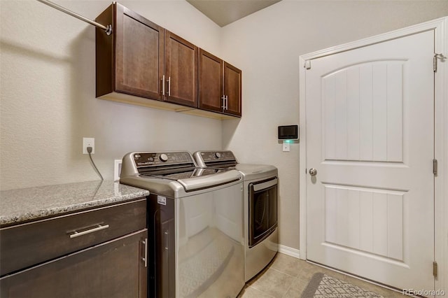 laundry area featuring washer and dryer, cabinets, and light tile patterned flooring